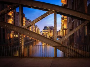 Eiserne Brücke über einem Kanal, erleuchtet von Gebäuden.