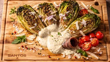 Grilled lettuce with sauce on wooden board.