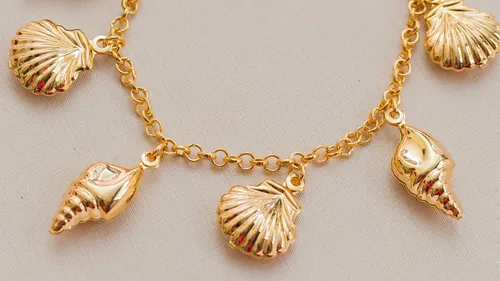 Goldene Muschel-Charms an einem Armband.