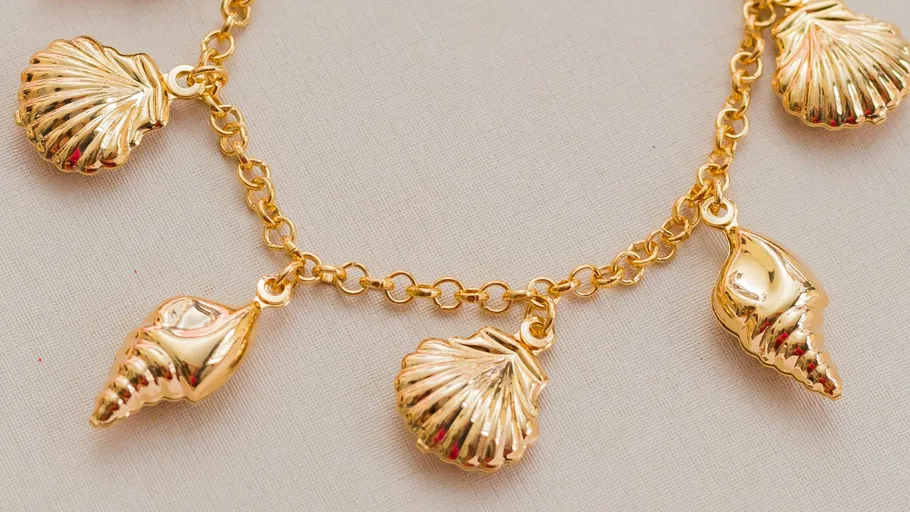 Golden seashell charms dangling on a bracelet.