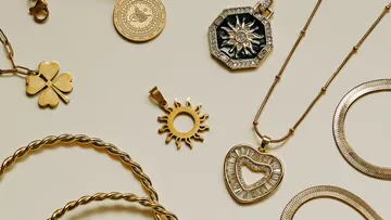 Gold jewelry pieces on beige background.