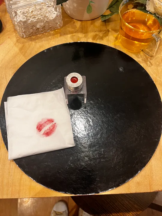 Serviette mit Lippenstiftabdruck auf schwarzem Teller.