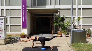 Woman practicing yoga outside a museum.