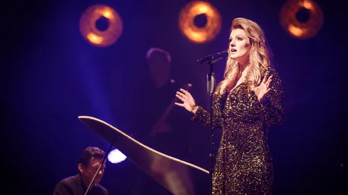 Singer performing on stage with spotlights.