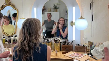 Frauen tragen Make-up am Schminktisch auf.