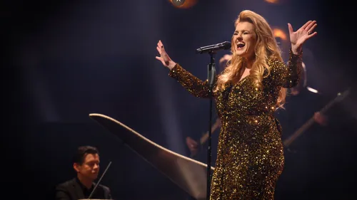 Woman singing on stage with microphone.