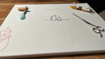 Stickzubehör auf Leinwand, Holztisch.