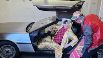 Two people in costume with a DeLorean.