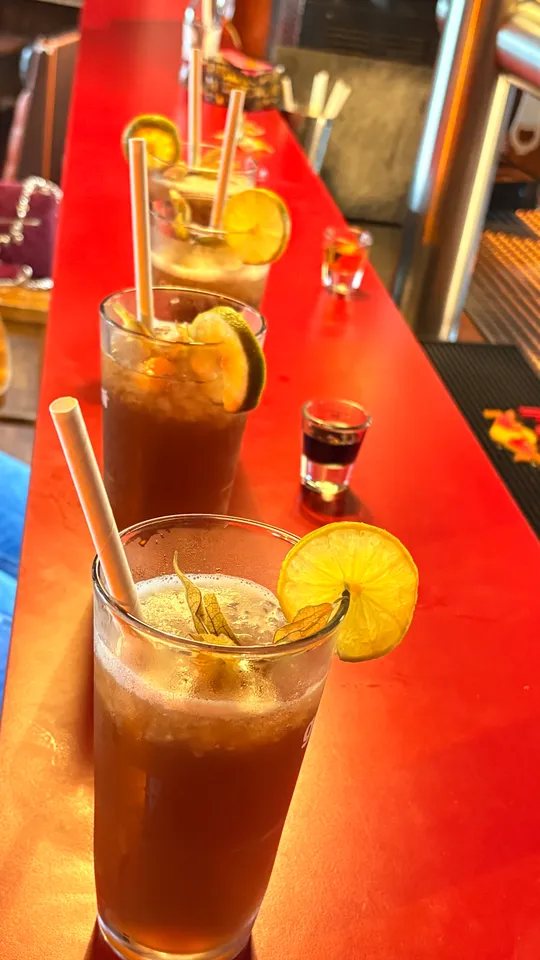 Cocktailgläser auf roter Bartheke.