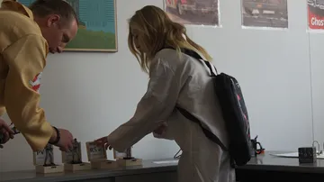 Two people examining items on a table.