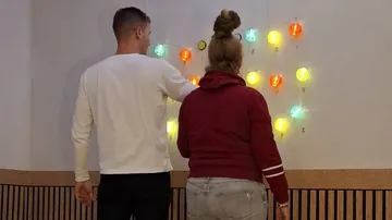 Two people interact with lit wall lights.