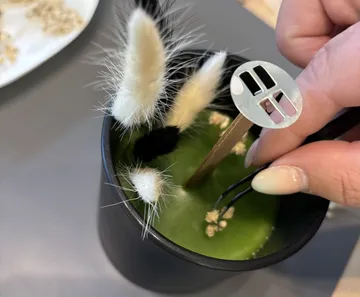Hand inserting object into green drink.