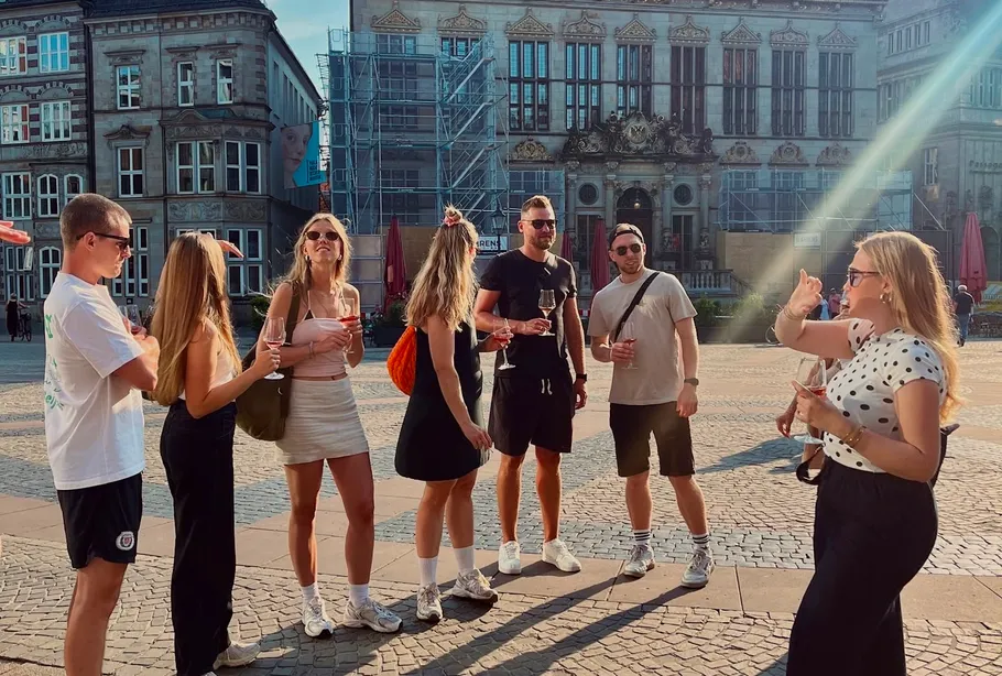Gruppe steht, spricht, hält Getränke auf Stadtplatz.