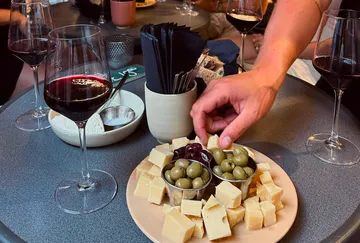 Hand greift nach Käse und Oliven auf Tisch.