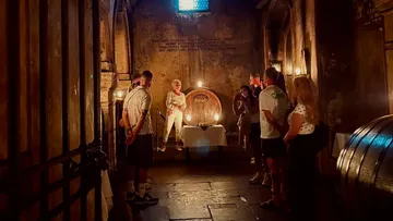 People in a dim wine cellar gathering.
