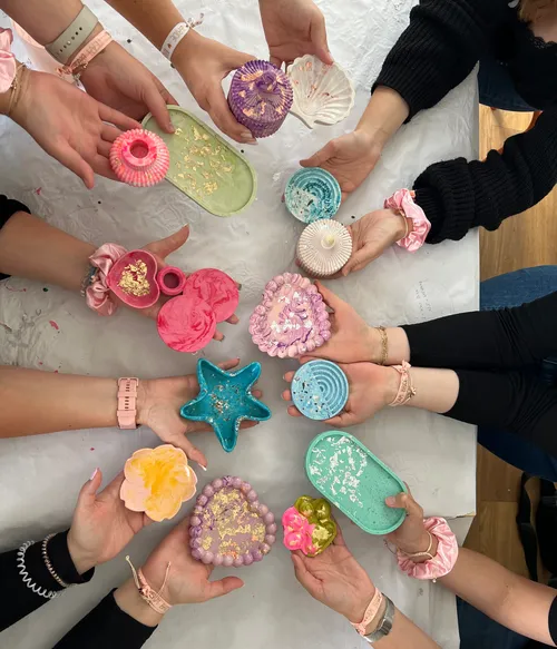 Hands holding colorful, creative resin crafts.
