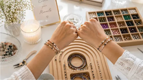 Hände zeigen Armbänder, umgeben von Perlen.