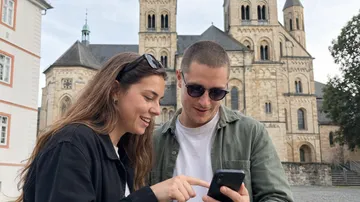 Paar nutzt Handy vor Kathedralenfassade.