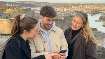 Three friends looking at smartphone outdoors.