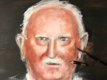 Portrait of an elderly man surrounded by drawing materials.
