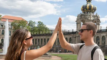 Two people high-fiving near historic building.