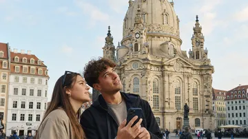 Paar schaut vor historischem Gebäude nach oben.