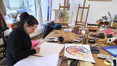 Woman drawing at a cluttered art studio.