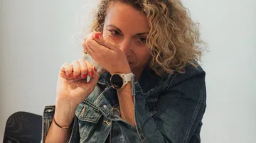 Frau riecht Handgelenk in Jeansjacke.