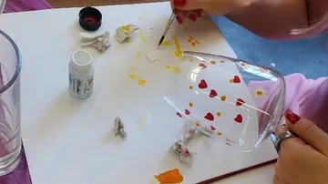 Glass cup painted with hearts on table.