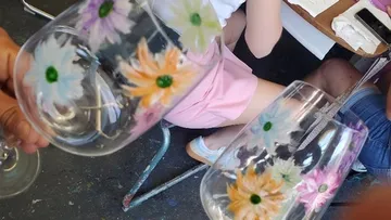 Painted glasses held by hands in classroom.