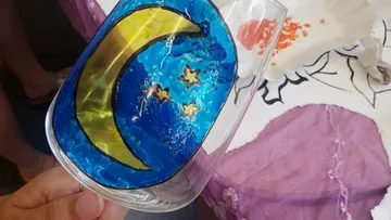 Glass with moon and stars design, hand-held.
