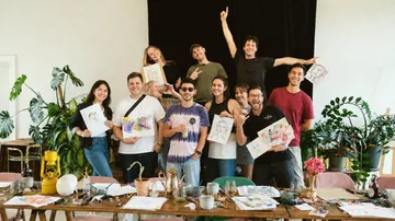 Group of people showing artwork at table.
