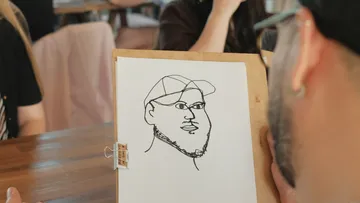 Man sketching portrait in cafe.