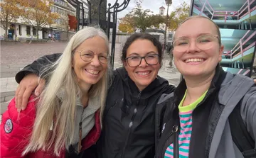 Three women smiling in outdoor setting.
