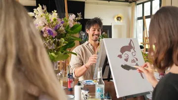 Mann malt mit Freunden im Kunststudio.