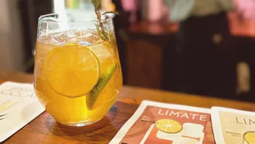 Glass of iced tea with lemon, wooden counter.
