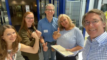 Gruppe von fünf lächelt in die Kamera draußen.