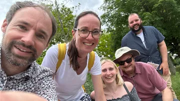 Gruppe von fünf Personen lächelt im Park.