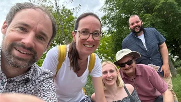 Fünf Personen lächelnd in einem Park.