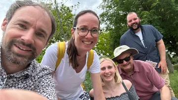 Gruppe von fünf Personen draußen lächelnd.