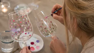Person bemalt Weingläser an einem Tisch.