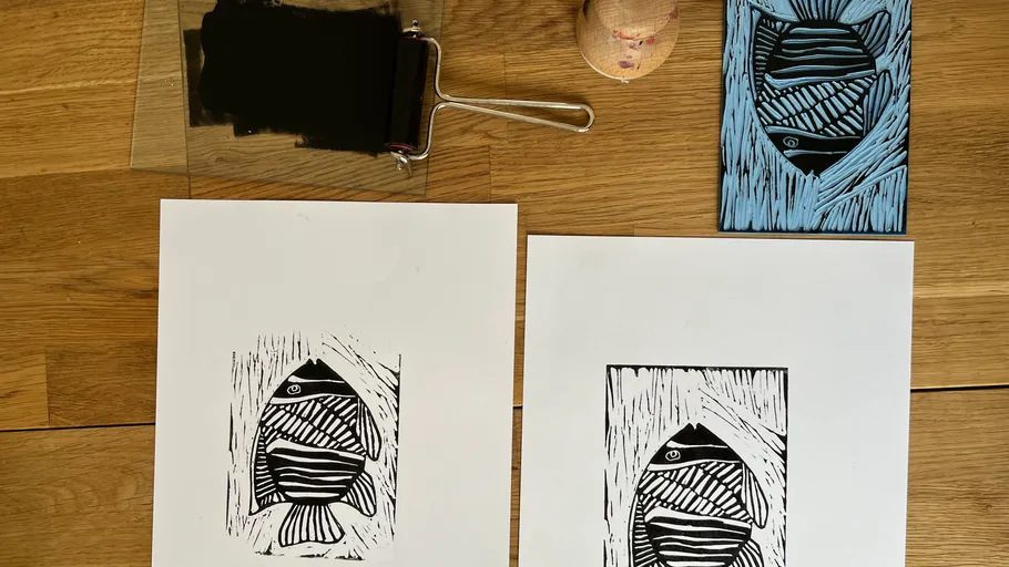 Fish prints on paper, ink roller nearby.