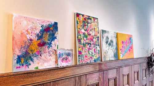 Abstract canvases displayed on wooden ledge.