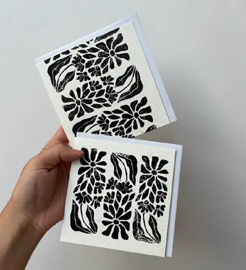 Hand holding two floral pattern cards.