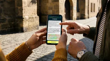 Personen nutzen Smartphone mit Karte draußen.