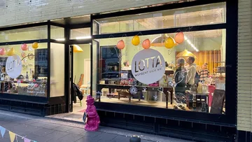 Schaufenster mit Luftballons und Menschen innen.