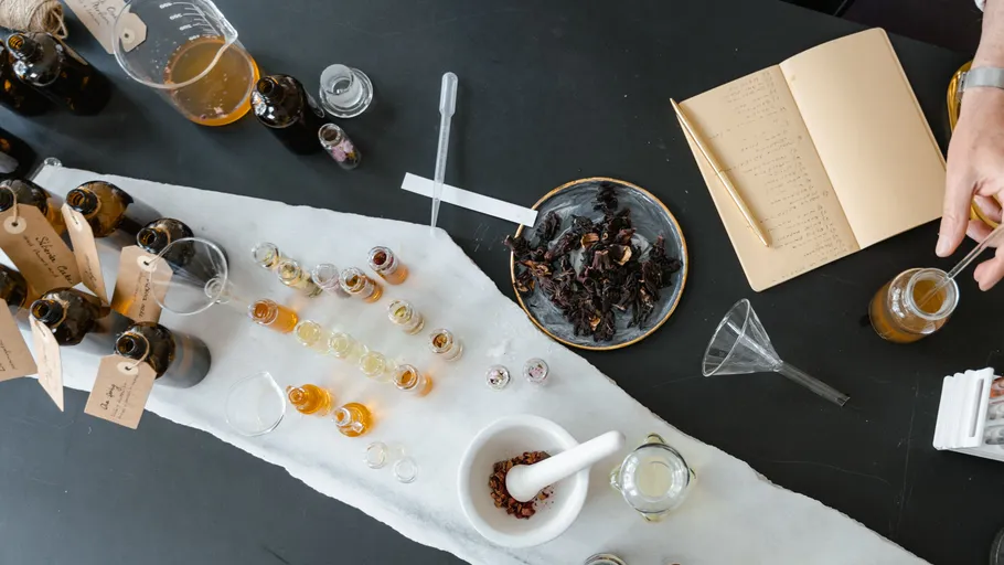 Hände experimentieren mit Flüssigkeiten auf schwarzem Tisch.
