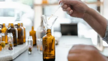 Hand benutzt Pipette in Flaschentrichter drinnen.