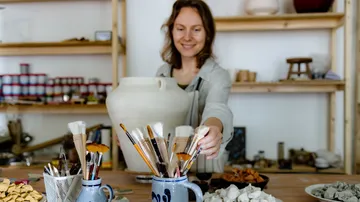 Frau hält Keramiktopf im Kunststudio.
