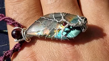 Hand trägt ein buntes Steinarmband.